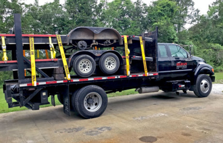 flat bed truck carries two flat bed trailers for construction site mobilization