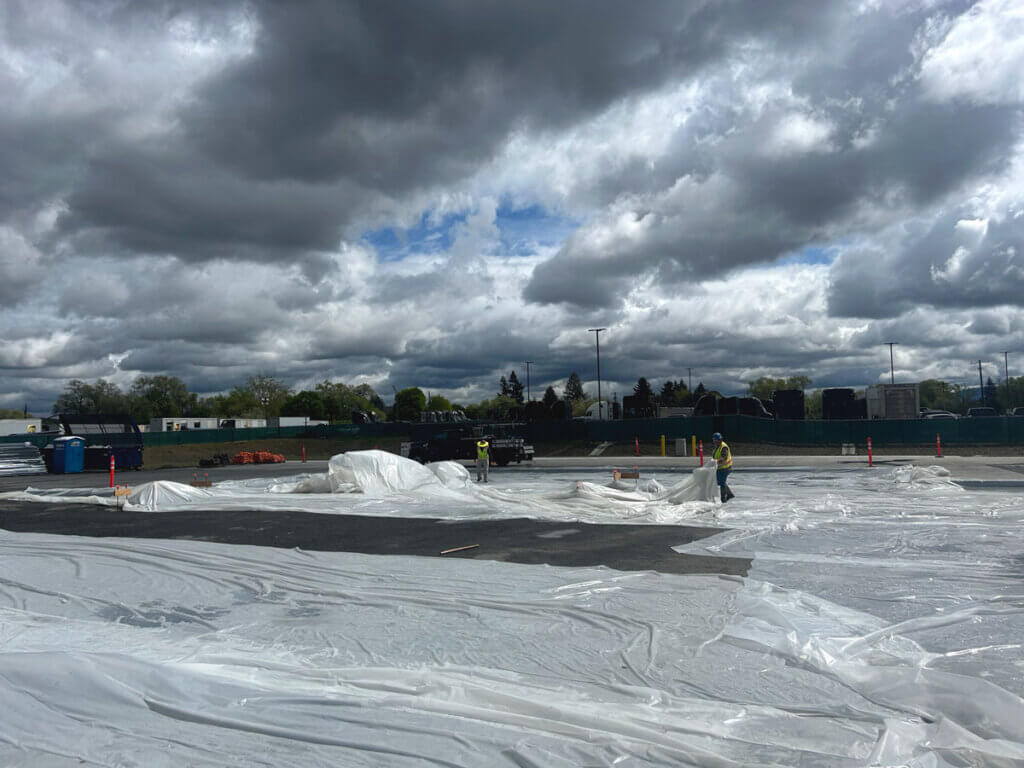 Curing concrete protected from rain by SilMan team during fast-track industrial construction.