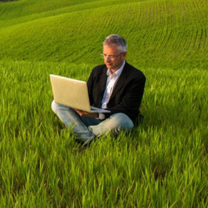 business man in farm field with laptop